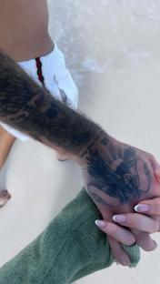 Close-up of two hands holding, one with visible tattoos.