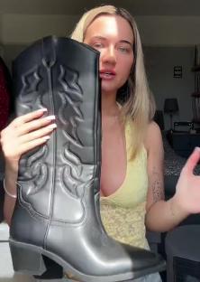 Person holding up a black cowboy boot.
