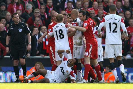 Soccer players clashing on the field, one player is injured and lying on the ground.
