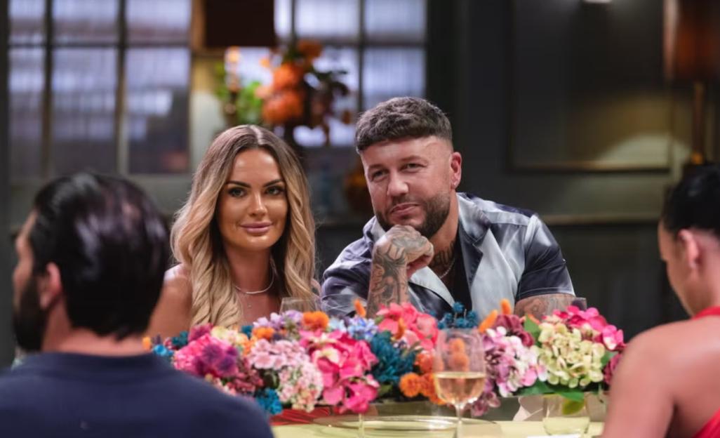 Amy and Adam from Married at First Sight sitting at a table with flowers.