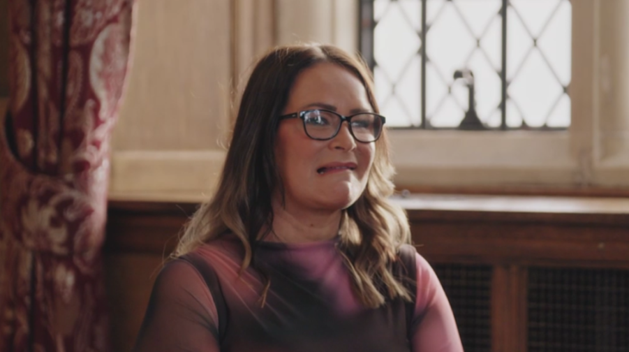 A woman with glasses making a cringing face.