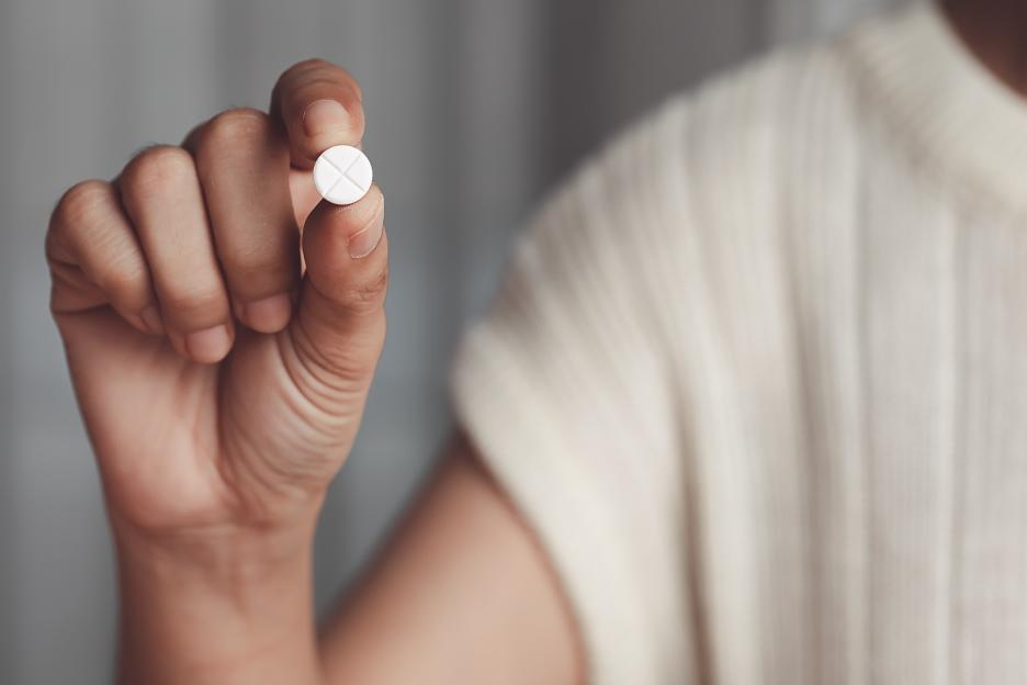 Hand holding a white pill.