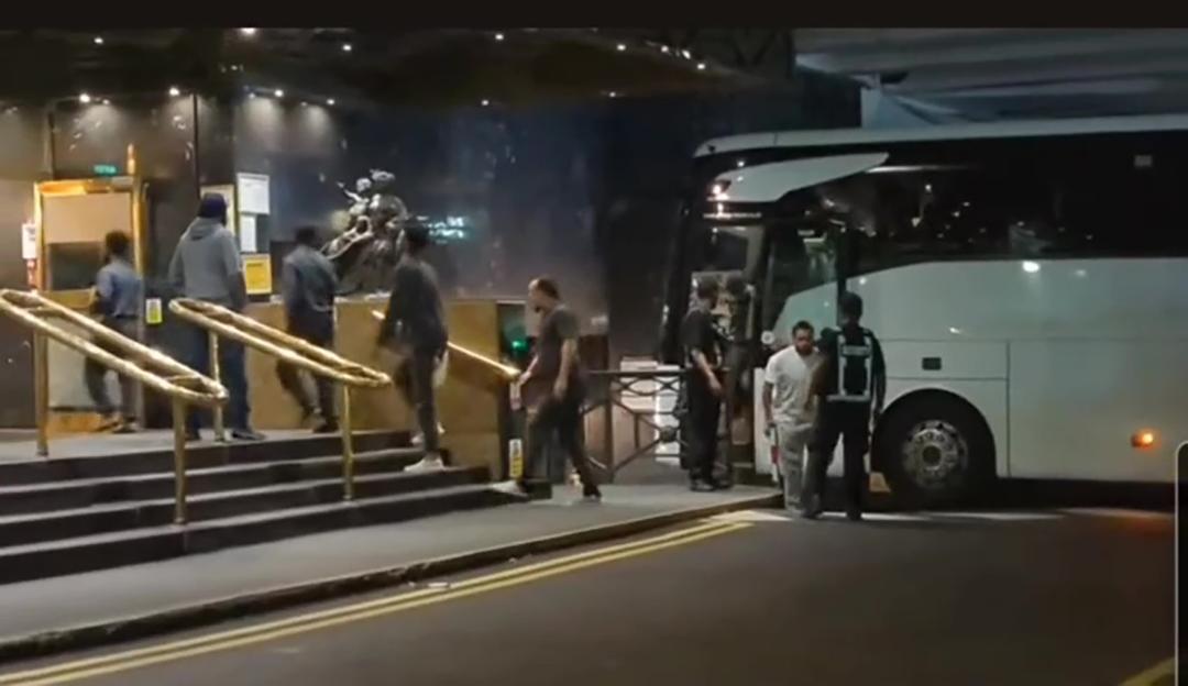 Migrants arriving at a hotel from a bus.