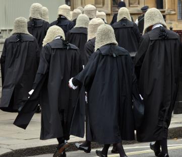 British judges in traditional robes and wigs walking in procession.