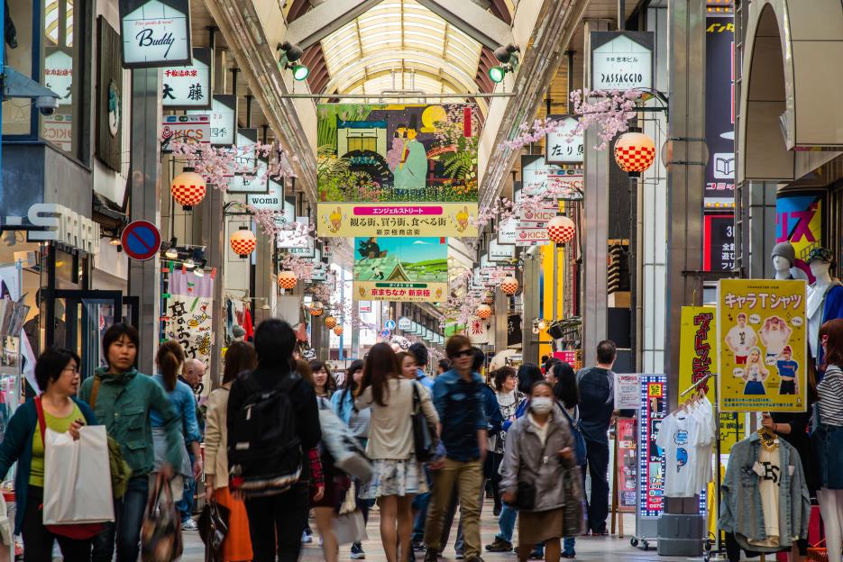 Teramachi Shopping Arcade in Kyoto, Japan, bustling with shoppers under a covered walkway adorned with decorative lanterns and banners.
