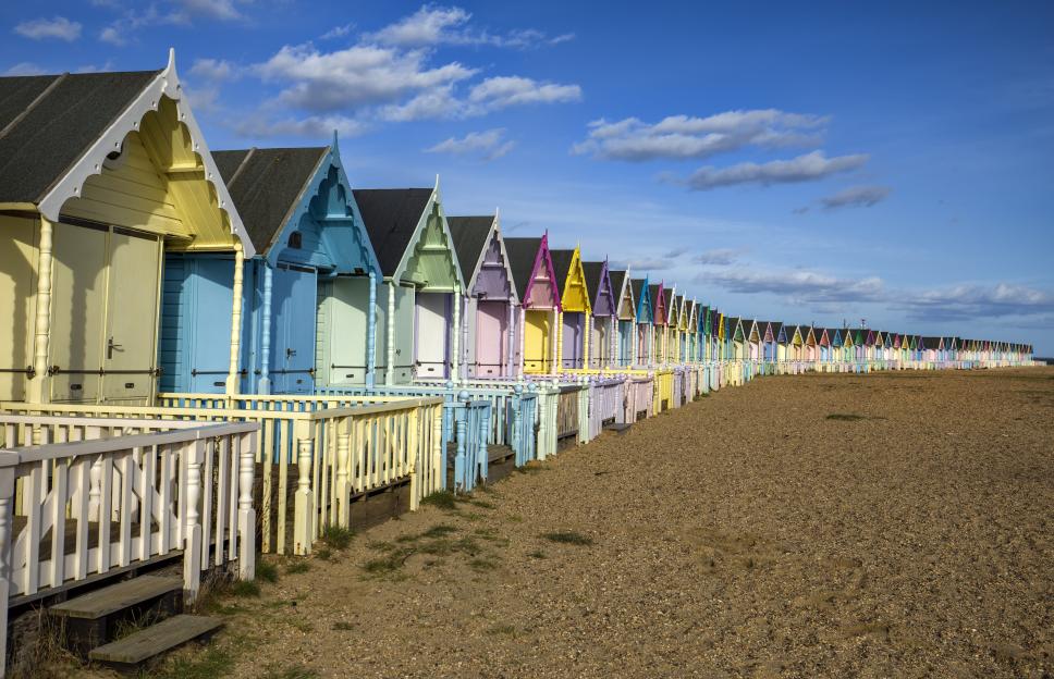 Row of colorful beach huts on a sandy beach.