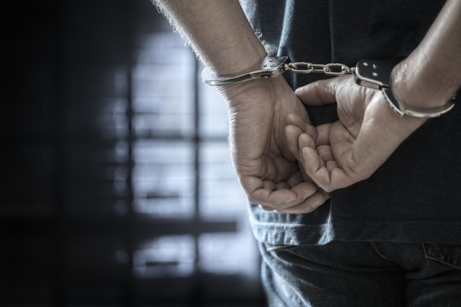 Man in handcuffs with hands behind his back.