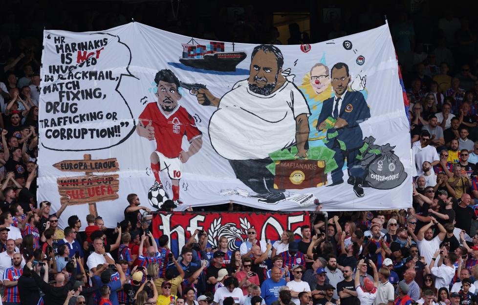 Crystal Palace fans display a banner with an illustration accusing Nottingham Forest's owner of corruption.