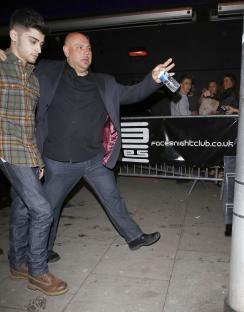 Zayn Malik leaving a nightclub, assisted by security.