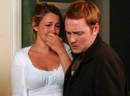 A crying woman begs a man not to leave.
