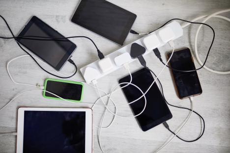 Multiple tablets and phones charging via a power strip.