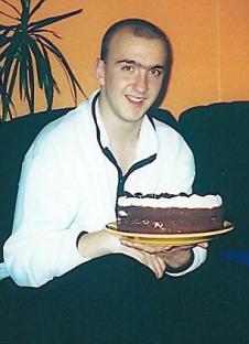 A young man holding a birthday cake.