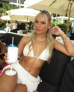Woman in white bikini holding a drink.