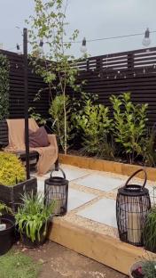 Small garden patio with stone pavers, wooden planters, and string lights.