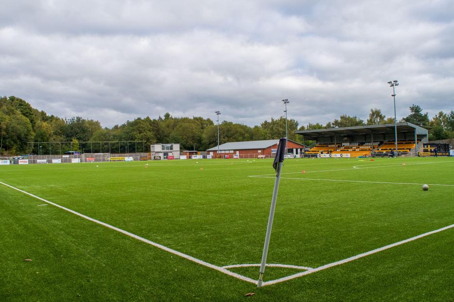 Soccer field with stands and trees in the background.