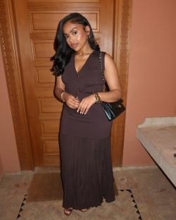 Woman in brown knit two-piece outfit and black purse.