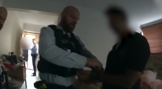 Police officers arresting a man in a house.