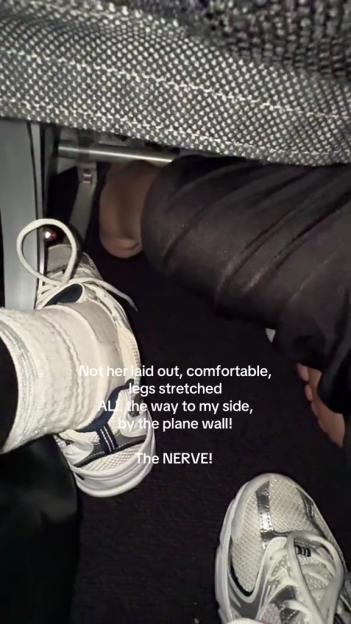 Airplane passenger's legs extending into another passenger's space.