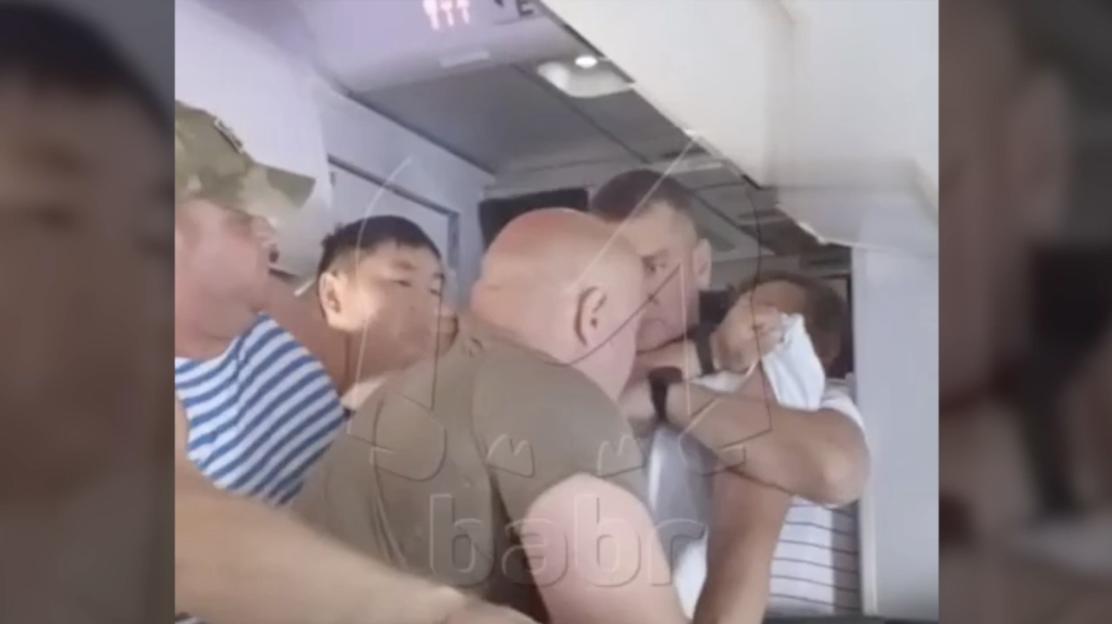 Passengers subduing a disruptive passenger on an airplane.