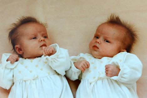 Twin baby girls in white dresses.