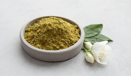Henna powder in a bowl with jasmine flowers.