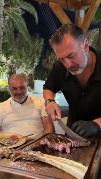 A man carving a large steak at a table outdoors.