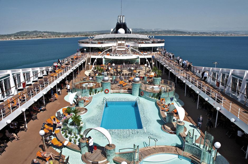 Cruise ship deck with pool and sunbathers.