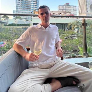 Man sitting outdoors holding a glass of wine.