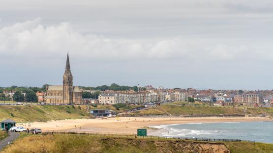 Long Sands beach in Tynemouth, England, with a church and buildings in the background.