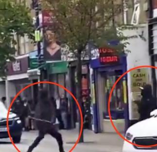 Video still of two men fighting with machetes in a street.