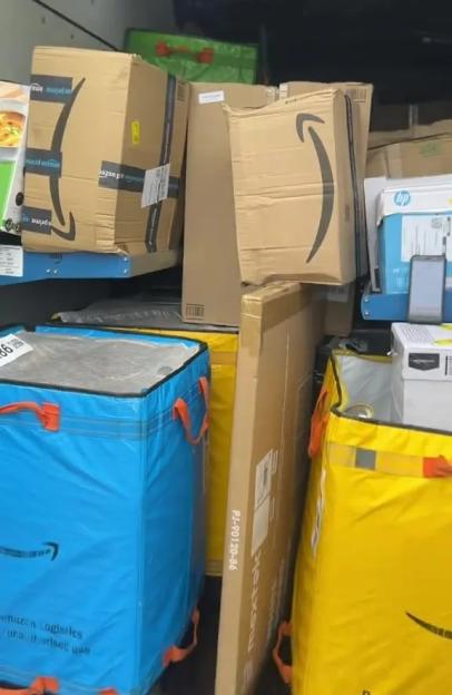 An Amazon delivery truck filled with packages and blue and yellow delivery bags.