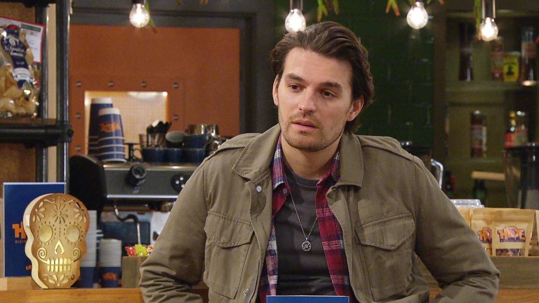 a man in a plaid shirt is sitting at a counter