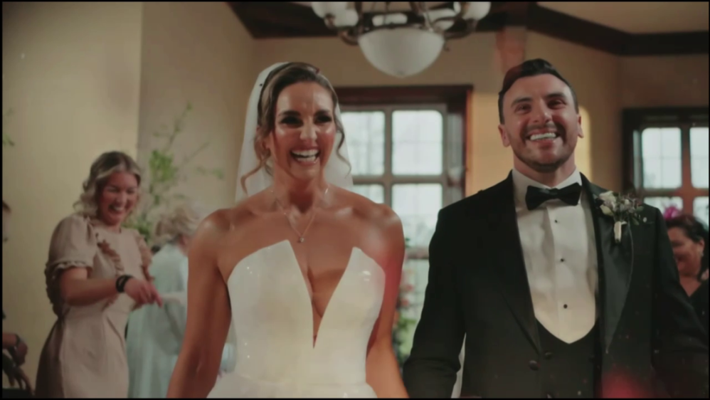 A bride and groom smiling and laughing as they walk down an aisle.