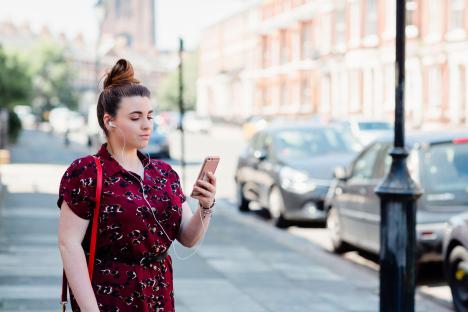 Woman using smartphone while listening to earphones.