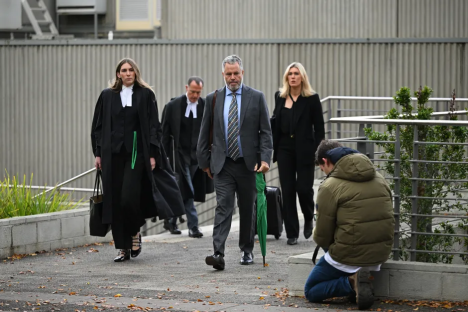 Lawyers and a person kneeling outside a courthouse.