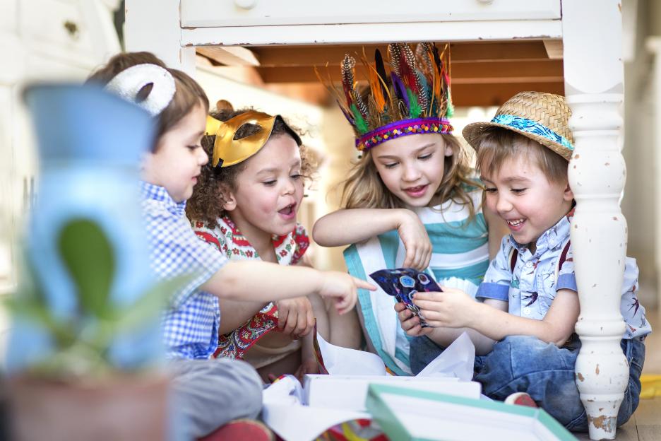 Four children opening presents at a birthday party.