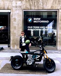 Man standing next to an electric BMW motorcycle outside a BMW Motorrad store.