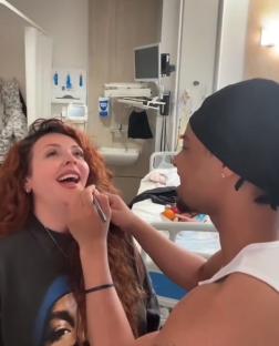 Jesy Nelson having her makeup applied in a hospital room.