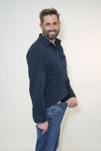 Man showing significant weight loss by holding up loose jeans.