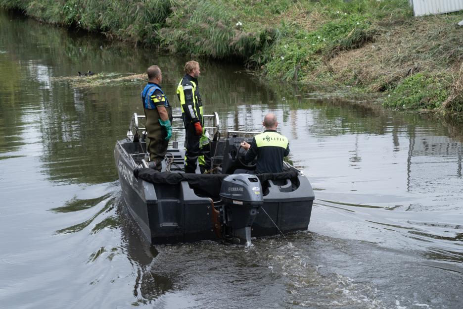 Police officers in a boat searching a canal.