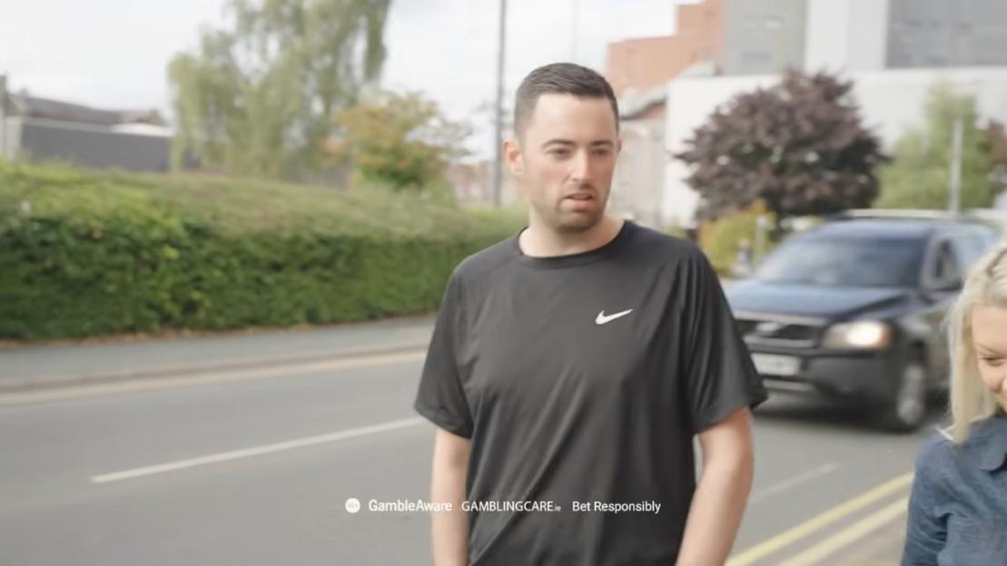 Luke Humphries in a black Nike t-shirt, walking with a woman on a street.