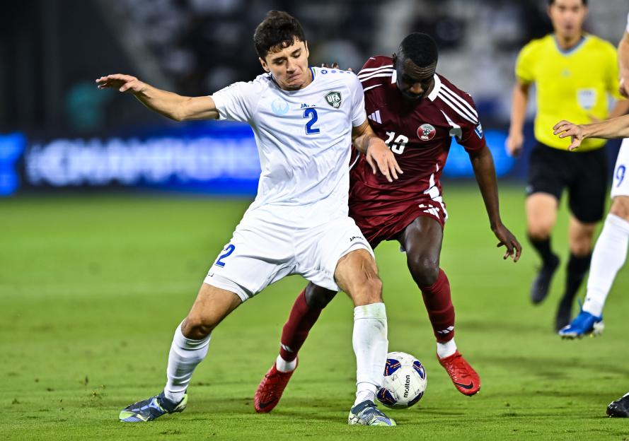 Almoez Ali of Qatar and Abdukodir Khusanov of Uzbekistan contest for the ball during a FIFA World Cup qualifier.