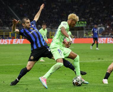 FC Barcelona's Lamine Yamal and FC Inter's Henrikh Mkhitaryan vying for the ball during a soccer match.