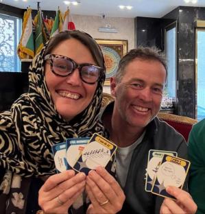 A woman and man holding game cards.