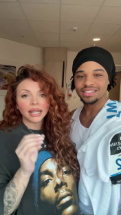 Jesy Nelson and a man, possibly her running partner, speak to the camera. The man is wearing a white shirt and a running bib.