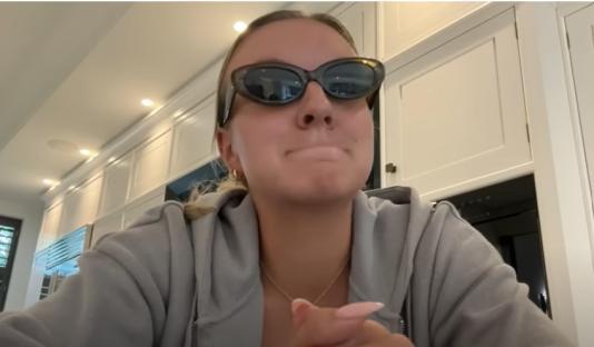 Woman wearing sunglasses in a kitchen.