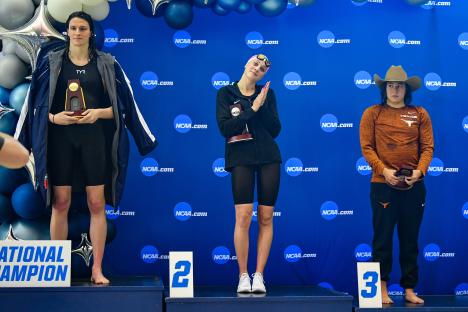 Three swimmers on a winners' podium at a swimming competition.