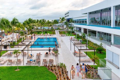Aerial view of a resort pool area with many people relaxing and swimming.