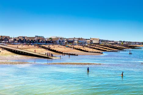 Whitstable beach with people swimming and relaxing.