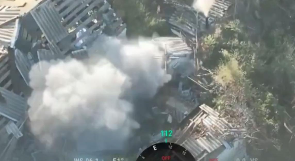 Aerial view showing smoke after a strike on a destroyed building, with a targeting reticle in the center.
